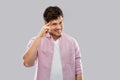 Smiling young man pointing finger to his head