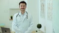 Smiling young man professional medic doctor wear white medical uniform looking at camera standing in hospital office.