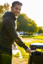 Smiling young man putting straws in garbage bin at park