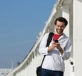 Smiling young man reading text message on mobile phone Royalty Free Stock Photo