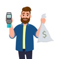 Smiling young man is showing or holding money bag, cash bag and POS terminal or credit, debit card swiping payment machine in hand Royalty Free Stock Photo