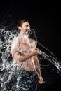 smiling young man showing thumb up while swilled with water splash