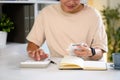 Smiling young man sits at a desk using a calculator and managing personal finances Royalty Free Stock Photo