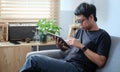 Smiling young man sitting on couch and working with digital tablet Royalty Free Stock Photo