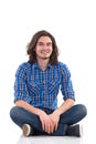 Smiling young man sitting on the floor with legs crossed. Royalty Free Stock Photo