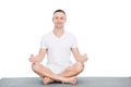 Athletic young man sitting on yoga mat and meditating