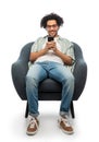 smiling young man with smartphone sitting in chair Royalty Free Stock Photo