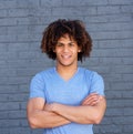 Smiling young man standing with arms crossed against gray wall Royalty Free Stock Photo