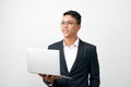 Smiling young man standing in black suit and glasses, holding open laptop Royalty Free Stock Photo