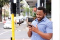 Smiling young man standing in city with cellphone Royalty Free Stock Photo