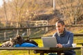 Smiling young man and three cats outdoors with a laptop Royalty Free Stock Photo