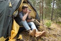 Smiling young man tourist sitting in touristic tent at the forest making photos on camera Royalty Free Stock Photo