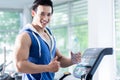 Smiling young man on treadmill holding water bottle Royalty Free Stock Photo