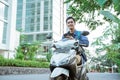 Smiling young man using a cellphone when riding a motorcycle Royalty Free Stock Photo