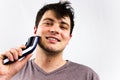 Smiling young man using electric shaver in front of mirror. Beauty, grooming and people concept. Handsome man using electric razor Royalty Free Stock Photo