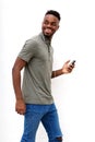 Smiling young man walking with mobile phone and earphones against white background Royalty Free Stock Photo