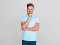 Smiling young man wearing a light blue polo t-shirt thinking Royalty Free Stock Photo