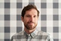 Smiling young man wearing a shirt matching his checkered wallpaper Royalty Free Stock Photo