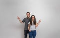 Smiling young man and woman pointing at copy space for advertisement on background. Happy couple wearing eyeglasses and casuals Royalty Free Stock Photo