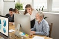 Smiling young manager helping senior worker with computer office Royalty Free Stock Photo