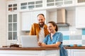 Smiling young married couple talking via video call using laptop at home in kitchen interior. Woman and man happy to Royalty Free Stock Photo