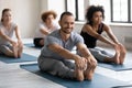 Smiling man practicing yoga at group lesson, Seated forward bend Royalty Free Stock Photo