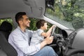 Smiling young man teaching little child to drive car in summer, boy hold steering wheel and look at road, profile Royalty Free Stock Photo