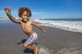 Smiling young mixed race boy running and playing at the beach while on a family vacation. Royalty Free Stock Photo