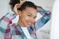 Smiling young mixed race girl holding healthy afro hairs, doing hairstyle. Natural beauty, self care Royalty Free Stock Photo