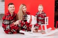 smiling young mom, dad are playing with baby boy on wooden rocking horse on the red background. happy family with little Royalty Free Stock Photo