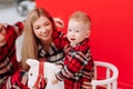 smiling young mom, dad are playing with baby boy on wooden rocking horse on the red background. happy family with little Royalty Free Stock Photo