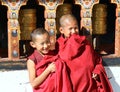 Smiling young monks standing by the religious prayer wheels at Paro Rinpung dzong, Paro, Bhutan