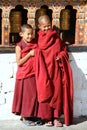 Smiling young monks standing by the religious prayer wheels at Paro Rinpung dzong, Paro, Bhutan