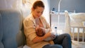 Smiling young mother breastfeeding her newborn baby boy in bed before going to sleep. Concept of healthy and natural Royalty Free Stock Photo