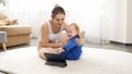 Smiling young mother doing baby massage and body stretching to her little son while watching video on tablet computer. Family Royalty Free Stock Photo