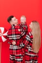 smiling young mother and father are kissing and hugging their baby boy on red background. concept of love and Royalty Free Stock Photo