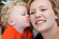 Smiling young mother gets kiss from her little boy. Royalty Free Stock Photo