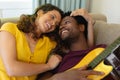 Smiling young multiracial couple romancing while lying with guitar at home Royalty Free Stock Photo