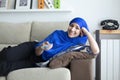 Smiling young Muslim woman lying on sofa watching TV