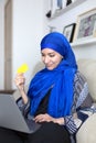 Smiling young muslim woman shopping online from home with credit card Royalty Free Stock Photo