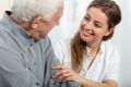 Smiling nurse sitting at table with senior patient