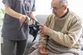 Smiling young nurse taking old man's blood pressure Royalty Free Stock Photo