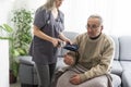 Smiling young nurse taking old man's blood pressure Royalty Free Stock Photo