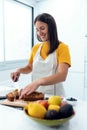 Smiling young nutritionist cutting carrot cake into small pieces in the kitchen at home