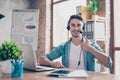 Smiling young operator of call center sitting at the table and s Royalty Free Stock Photo