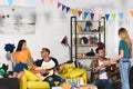 smiling young people with pizza beer and guitar having fun together at home