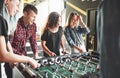 Smiling young people playing table football while indoors Royalty Free Stock Photo