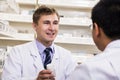 Smiling young pharmacist showing prescription medication to a customer