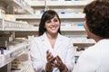 Smiling young pharmacist showing prescription medication to a customer