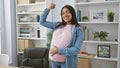 Smiling young pregnant woman, confident business worker, exuding power with a strong gesture, touching her belly in the office, Royalty Free Stock Photo